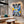 Cuadro de collage urbano amarillo y lila en MDF en sala de concreto con sofá curvo y mesa de mármol