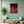 Cuadro de mano y triángulos de neón rojo en MDF en sala verde menta con sofá a juego y planta