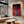 Cuadro de mano y triángulos de neón rojo en MDF en sala de concreto con sofá curvo y mesa de mármol
